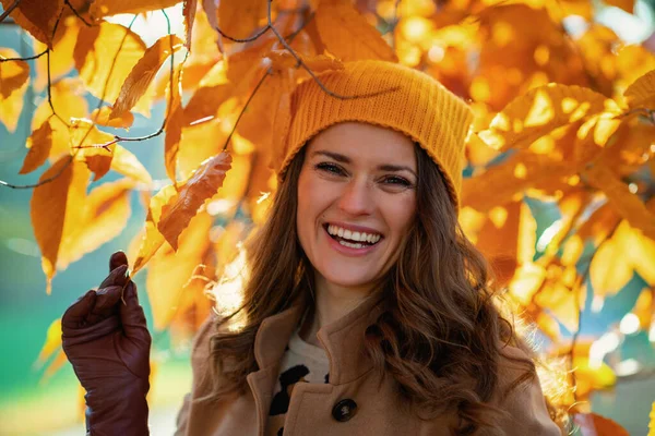 10月だ 幸せな中年女性ですベージュコートとオレンジの帽子秋に市内公園の外の紅葉の間で — ストック写真