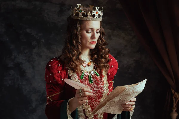 Pensive Middeleeuwse Koningin Rode Jurk Met Perkament Kroon Donkergrijze Achtergrond — Stockfoto