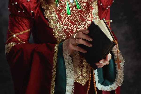 穿着红色衣服的中世纪女王的衣服 带有书和深灰色背景的念珠 — 图库照片
