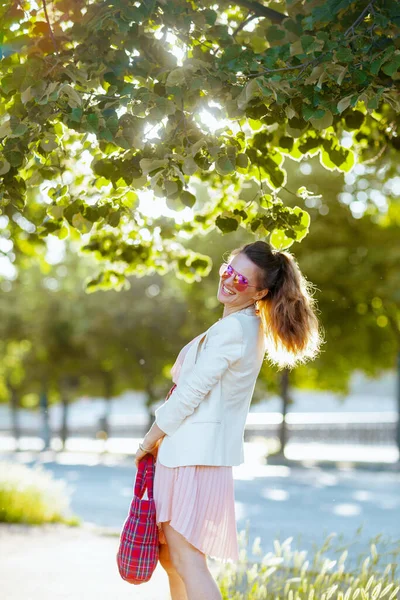 城市里快乐优雅的40岁女人 身穿粉色衣服和白色夹克 头戴红包和太阳镜 — 图库照片