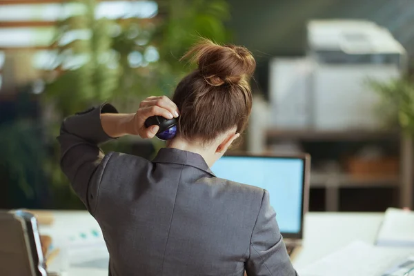 持続可能な職場 現代の緑のオフィスで灰色のビジネススーツの現代のビジネス女性の後ろから見た首にマッサージローラーを使用して — ストック写真