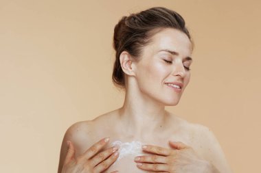 Rahatlamış modern kadın vücut kremi bej üzerine izole edilmiş..