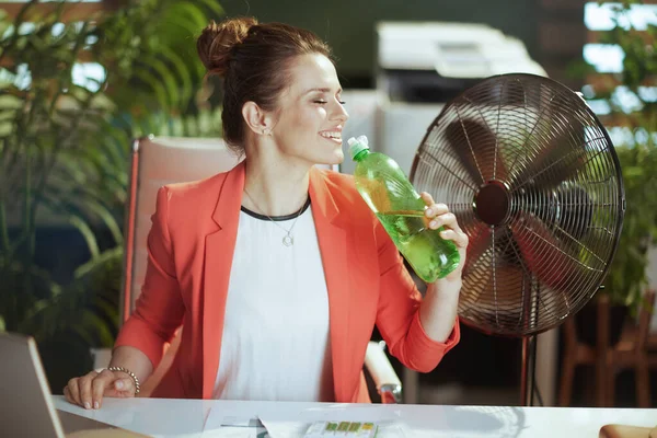 持続可能な職場 幸せな現代のビジネス女性が仕事で赤いジャケットに水と電気ファンのボトル — ストック写真