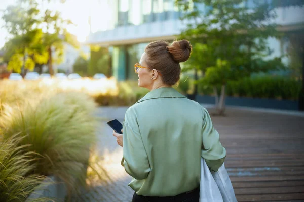 用智能手机从商业中心附近的中年妇女身后看到绿色衬衫 — 图库照片