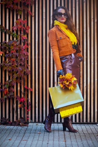 十一月 全长肖像画 城市里穿着橙色风衣 头戴购物袋 头戴秋天黄叶的时髦女性 — 图库照片