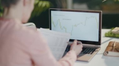 Bilgisayarlı, finansal tabloları kontrol eden ve modern ofiste online yatırım verileri alışverişi yapan modern bir kadın tarafından görüldü..