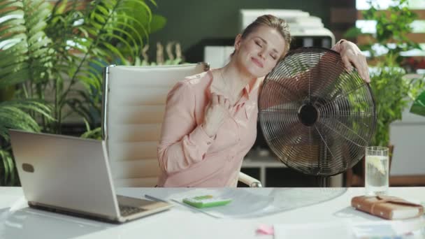 可持续工作场所 快乐的现代中年女性员工 在现代绿色办公室里 带着电扇和笔记本电脑 — 图库视频影像