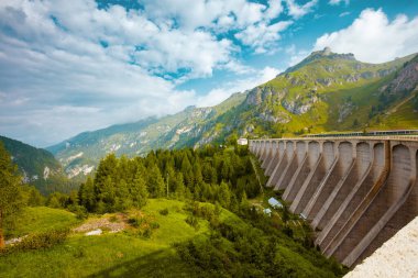 Dolomitlerde yaz zamanı. Dağlar, tepeler, bulutlar, çayırlar, ağaçlar ve baraj manzarası.