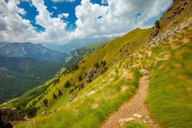 Dolomitlerde yaz zamanı. Dağlarla, tepelerle, bulutlarla, otlarla ve patikalarla dolu manzara.