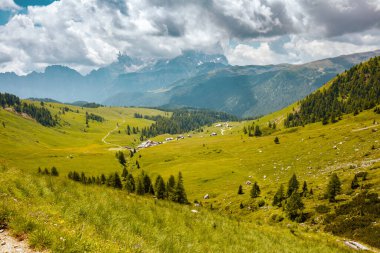 Dolomitlerde yaz zamanı. Dağlı, tepeli, bulutlu ve ağaçlı manzara.