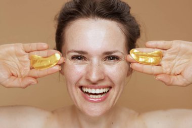 Bej arka planda göz bantları olan mutlu modern bir kadın..