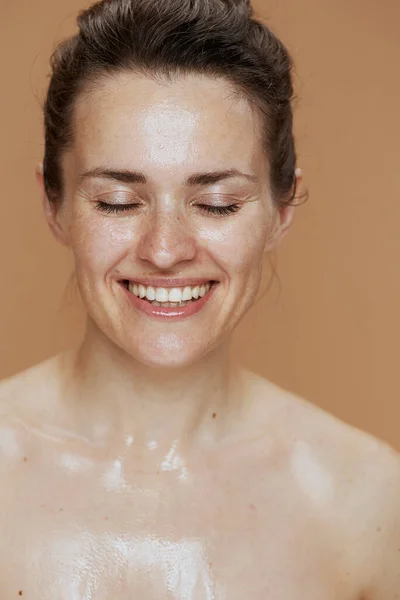 在米色背景下洗脸时微笑的年轻女人 — 图库照片