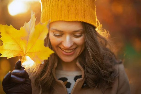 10月份 城市公园里 身穿米黄色外套 头戴橙色帽子 头戴秋天黄色叶子的中年妇女笑了 — 图库照片