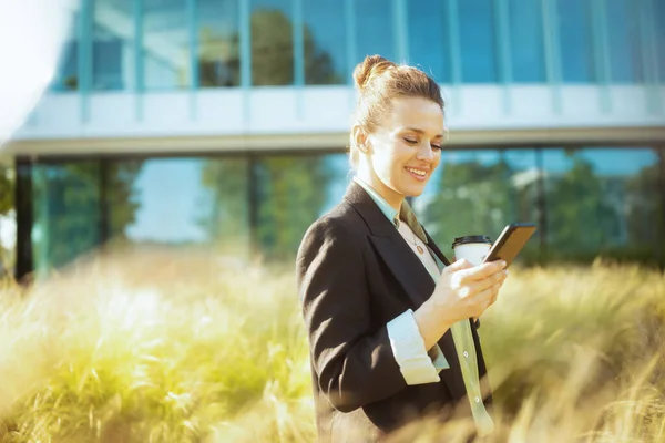 Lächelnde Moderne Angestellte Mittleren Alters Schwarzer Jacke Mit Smartphone Und Stockbild
