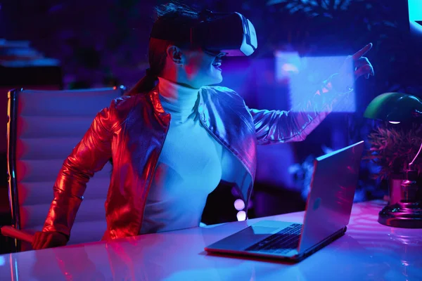 霓虹灯元的未来主义概念 穿着Vr耳机设计现代办公室虚拟现实的快乐的40岁女人 — 图库照片