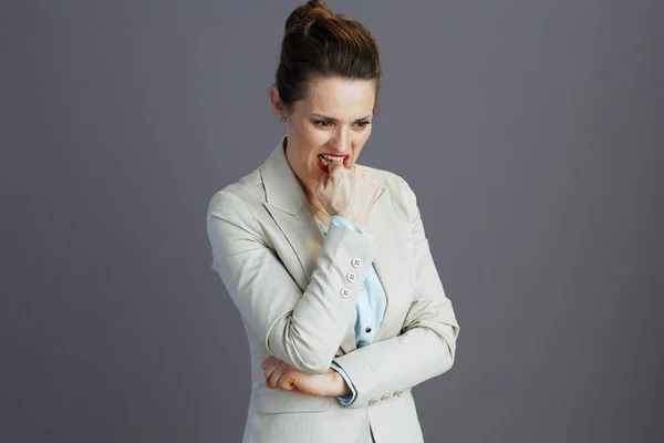 stressed stylish small business owner woman in a light business suit isolated on grey.