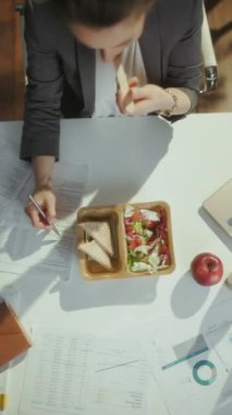 Sürdürülebilir iş yeri. Yeşil ofiste salata yiyen muhasebeci kadının üst görüntüsü..