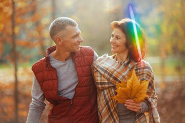 Merhaba sonbahar. Sonbahar yapraklarıyla parkta yürüyen güler yüzlü şık bir çift..