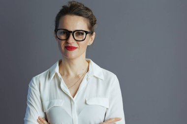 Beyaz bluzlu, gözlüklü ve gri arka planda vergi formlu moda bir kadın işçi..