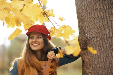 Merhaba sonbahar. 40 yaşında, kot gömlekli, kırmızı şapkalı, güz yapraklı ve eşarplı mutlu bir kadın..