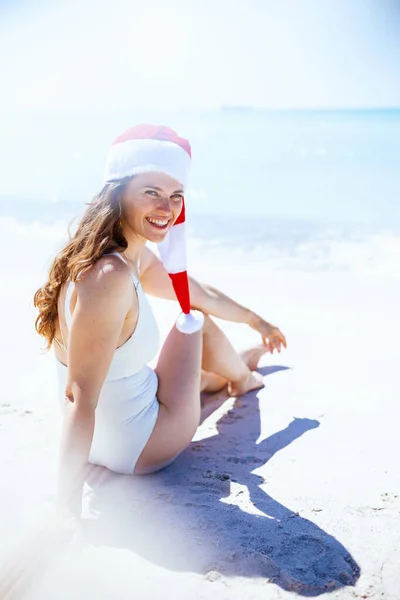 Uśmiechnięta Nowoczesna Kobieta Białych Strojach Plażowych Paski Świąteczny Kapelusz Siedząca — Zdjęcie stockowe