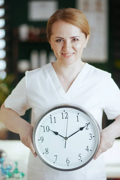 Healthcare time. happy massage therapist woman in massage cabinet with clock.