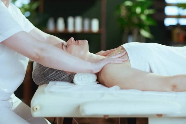 Healthcare time. medical massage therapist in massage cabinet massaging clients shoulder on massage table.