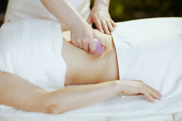 Healthcare time. Closeup on massage therapist in spa salon with silicone massage cup massaging clients stomach.