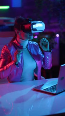 Neon metaverse futuristic concept. smiling modern woman in virtual reality goggles exploring metaverse in modern office.