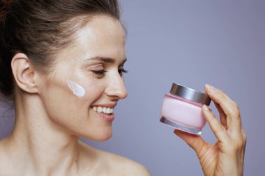 Mutlu modern 40 yaşındaki kadın kozmetik krem kavanozu ile mavi üzerine izole edilmiş..