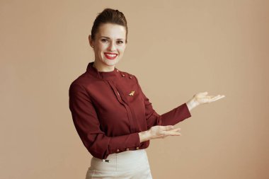 Gülümseyen stil sahibi bayan hostes bej arka planda.