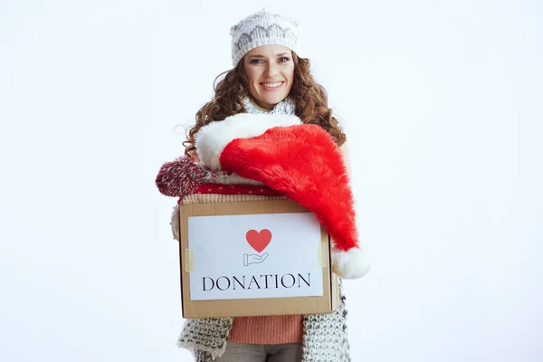 Hello winter. smiling stylish woman in sweater, mittens, hat and scarf isolated on white background with santa hat and donation box.