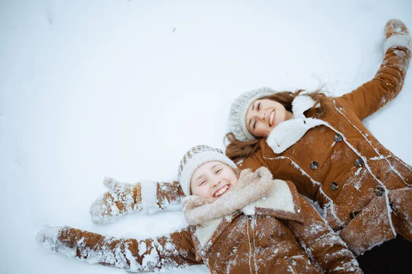 穿着外套 围巾和手套的优雅的母亲和孩子们在城市公园的室外让雪天使们微笑 — 图库照片