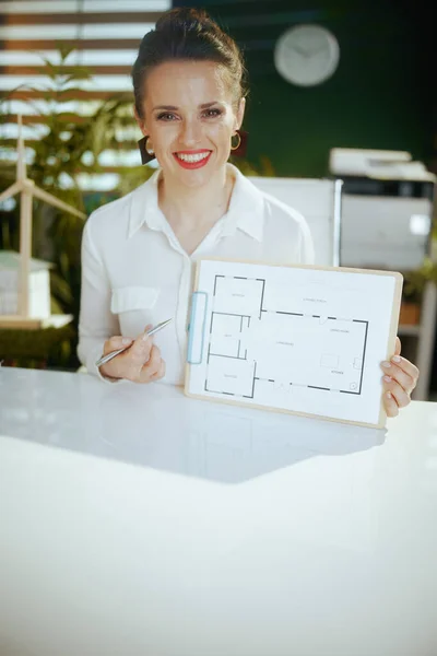 Time to move on. smiling elegant 40 years old woman real estate agent in modern green office in white blouse with clipboard and building plan.