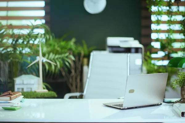 生态房地产业 现代绿色办公室的书桌 装有笔记本电脑 图库图片