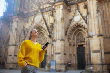 Prag Cumhuriyeti 'nde sarı bluzlu, akıllı telefonlu, gezintiye çıkmış, gezintiye çıkmış mutlu, modern yalnız bir turist kadın..