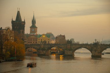 Vltava Nehri, Charles Köprüsü ve sonbaharda Prag, Çek Cumhuriyeti 'nde günbatımında tekne manzarası.