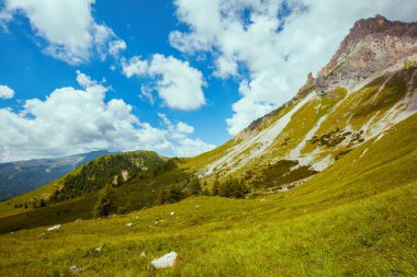 Dolomitlerde yaz zamanı. Dağlarla, tepelerle, bulutlarla, çayırlarla ve ağaçlarla dolu bir manzara.