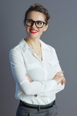 Gülümseyen 40 yaşında beyaz bluzlu, gri gözlükleri olan bir iş kadını..