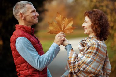 Merhaba sonbahar. Parktaki mutlu modern çift güz yaprağıyla.