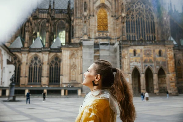 在布拉格 穿着黄色衬衫和雨衣的沉思的现代女性正享受着散步 — 图库照片