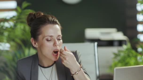 持続可能な職場 現代のグリーンオフィスでサラダを食べる灰色のビジネススーツの現代的な中年のビジネス女性を笑顔 — ストック動画
