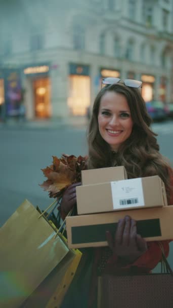 10月だ 幸せな中年女性でオレンジトレンチコートで小包と秋の黄色の葉で街 — ストック動画