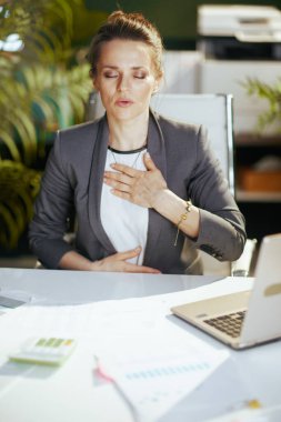 Sürdürülebilir iş yeri. Modern yeşil ofisteki rahat, küçük işletme sahibi kadın laptopuyla nefes egzersizi yapıyor..