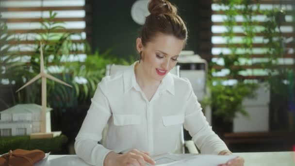 エコ不動産事業について 計算機と文書が付いている白いブラウスの現代緑のオフィスの優雅な女性のリアクターのクローズアップ — ストック動画