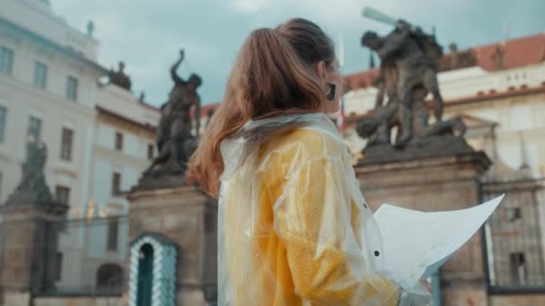 捷克共和国布拉格城堡附近身穿黄色上衣和雨衣 头戴地图的年轻女子大吃一惊 — 图库视频影像