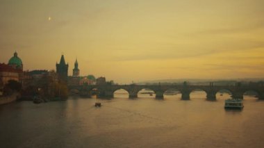 Vltava Nehri, Charles Köprüsü ve sonbaharda Prag, Çek Cumhuriyeti 'nde günbatımında tekne manzarası.
