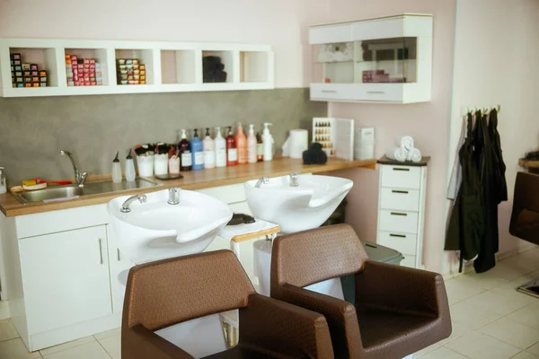 modern beauty salon with chairs, bottles of hair care products and salon backwash unit.