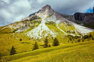 Dolomitlerde yaz zamanı. Dağlarla, bulutlarla, çayırlarla ve ağaçlarla dolu bir manzara.