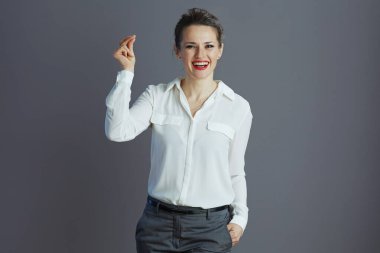 Beyaz bluzlu mutlu kadın işçi parmak şıklatması gri arka planda izole edilmiş..